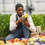 gardener inspects flowers in a pot in greenhouse ysjzsqc.jpg